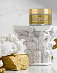 Gold container labeled 'Presidential body butter' on a decorative white pedestal with gold accents.